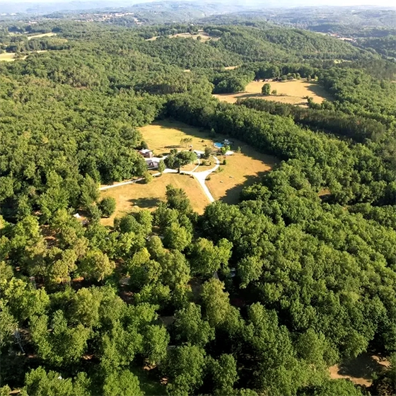 Vue aérienne du camping écologique La Clairière dans le Lot montrant l'implantation en pleine forêt sur 10 hectares